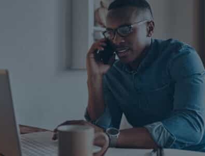 A man looking at a laptop on the phone